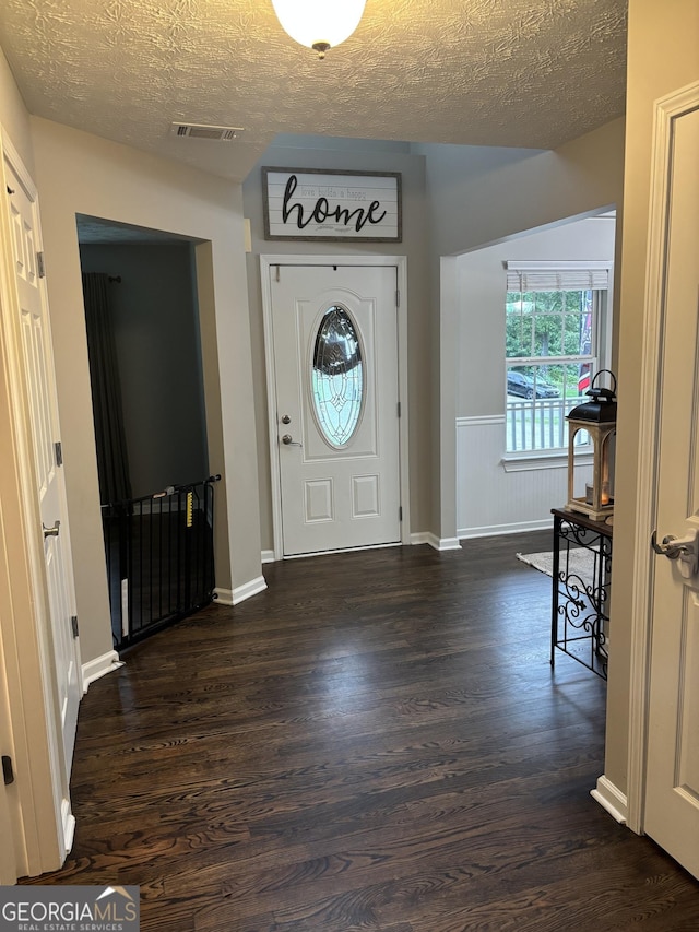 entryway with dark wood finished floors, a textured ceiling, and baseboards