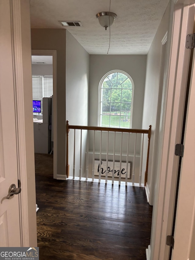 hall featuring dark wood finished floors, an upstairs landing, and baseboards