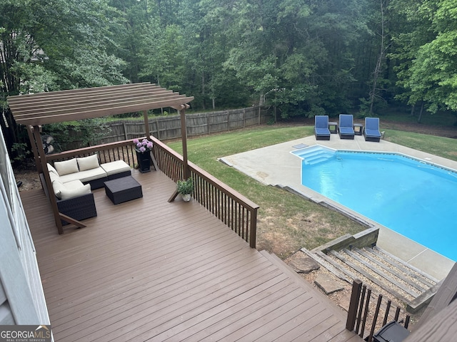 view of pool with a wooden deck, an outdoor living space, a forest view, and a patio area