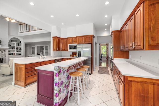 490 Water Wheel Ct, Cornelia, GA 30531 - kitchen with appliances with stainless steel finishes, light tile patterned floors, a kitchen breakfast bar, light countertops, and brown cabinetry
