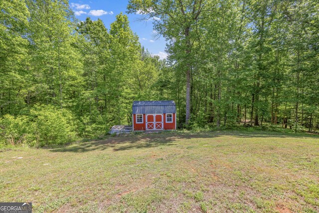 490 Water Wheel Ct, Cornelia, GA 30531 - view of grassy yard featuring a shed, an outdoor structure, and a wooded view