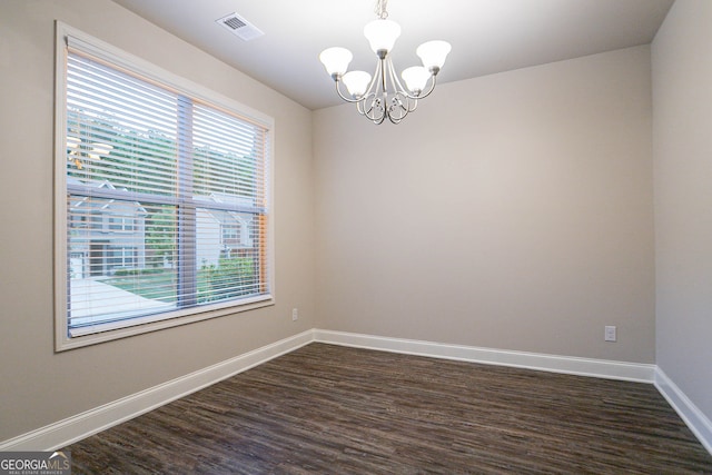 empty room with a chandelier, dark wood-type flooring, and baseboards