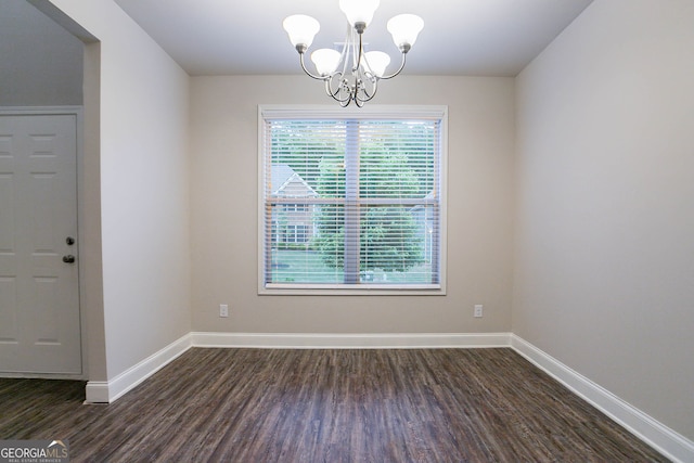 unfurnished dining area featuring plenty of natural light, a chandelier, dark wood-type flooring, and baseboards