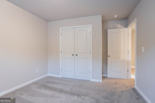 unfurnished bedroom with carpet, baseboards, and a closet