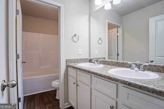 full bath featuring wood finished floors, toilet, double vanity, and shower / bath combination