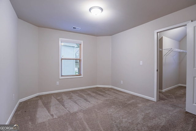 unfurnished bedroom featuring carpet flooring, a walk in closet, baseboards, and a closet