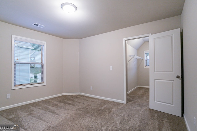 unfurnished bedroom with multiple windows, carpet floors, and a walk in closet