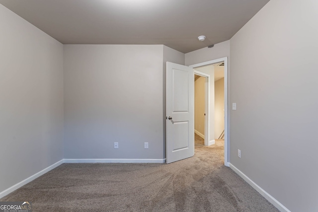 unfurnished room with carpet flooring, baseboards, and a smoke detector