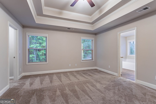 unfurnished room with carpet floors, a tray ceiling, crown molding, ceiling fan, and baseboards