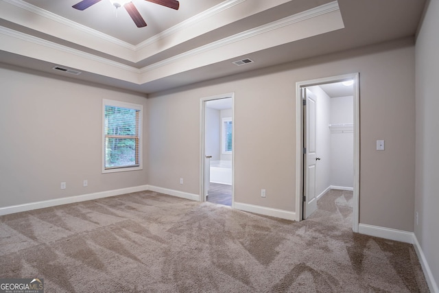 unfurnished bedroom featuring crown molding, carpet floors, a spacious closet, ensuite bathroom, and baseboards