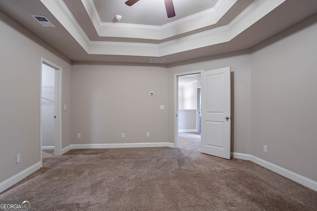 unfurnished room with a tray ceiling, crown molding, carpet floors, ceiling fan, and baseboards