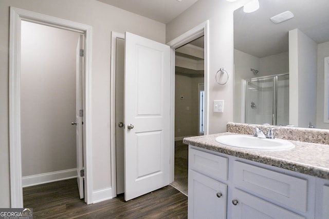 bathroom featuring wood finished floors, a shower stall, baseboards, and vanity