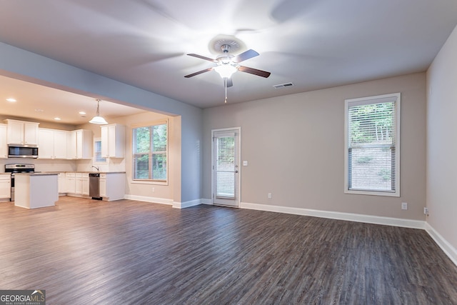 unfurnished living room with dark wood-style floors, healthy amount of natural light, a ceiling fan, baseboards, and recessed lighting