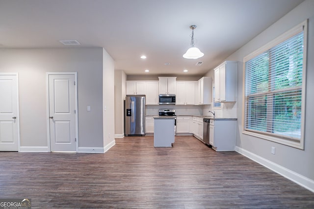 kitchen featuring appliances with stainless steel finishes, a sink, dark wood-style floors, baseboards, and white cabinetry