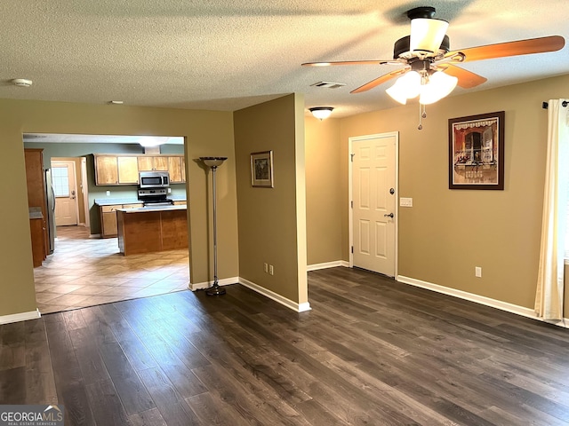unfurnished living room with ceiling fan, dark wood-type flooring, a textured ceiling, and baseboards