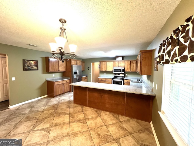 kitchen with stainless steel appliances, light countertops, a peninsula, a chandelier, and a textured ceiling