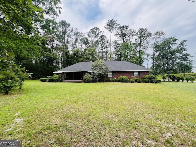 view of grassy yard featuring a sunroom and view of wooded area