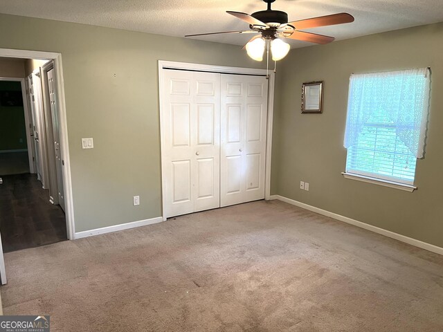 unfurnished bedroom featuring carpet floors, baseboards, a closet, ceiling fan, and a textured ceiling