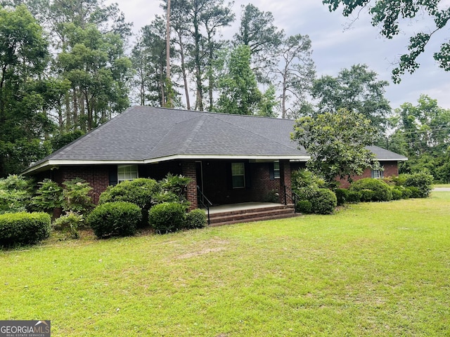 ranch-style home with a porch, a front lawn, roof with shingles, and brick siding