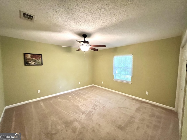 carpeted empty room with a ceiling fan, baseboards, and a textured ceiling