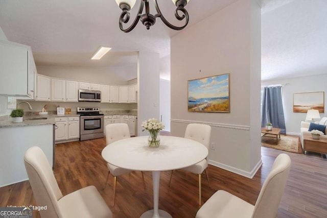 343 Ashton Way, Winder, GA 30680 - dining space featuring lofted ceiling, a chandelier, dark wood-style flooring, and baseboards