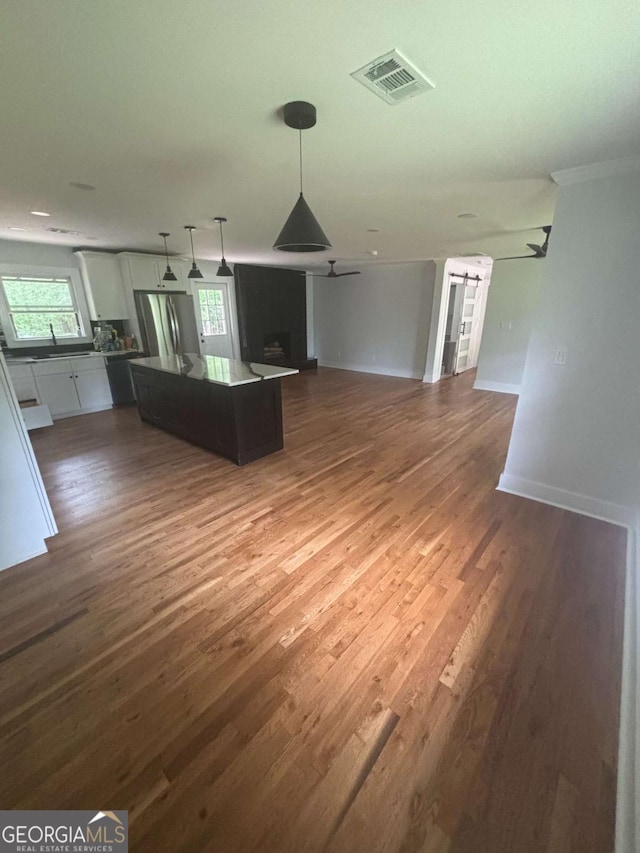unfurnished living room featuring a ceiling fan, healthy amount of natural light, and dark wood finished floors