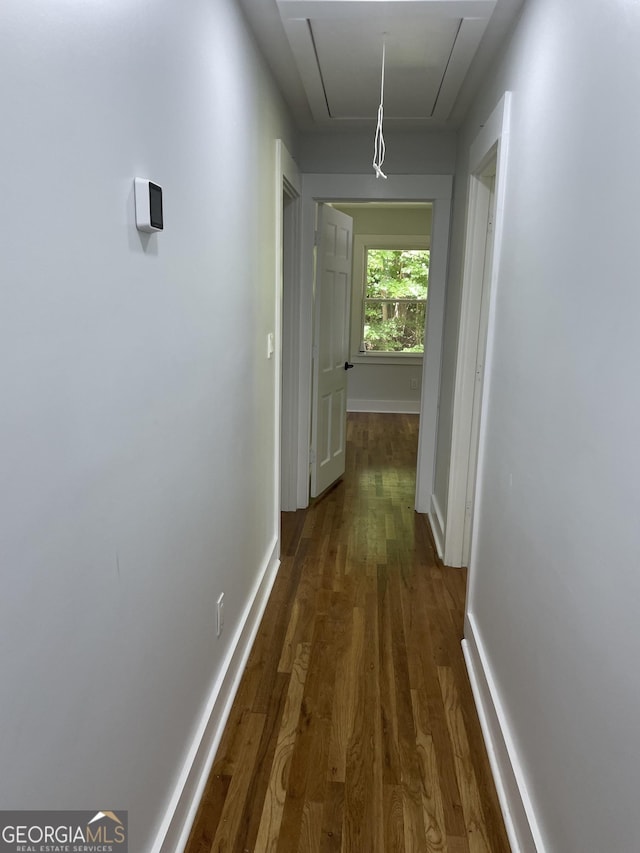 hall featuring attic access, wood finished floors, and baseboards