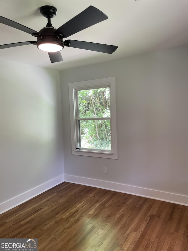 spare room featuring baseboards, ceiling fan, and dark wood finished floors