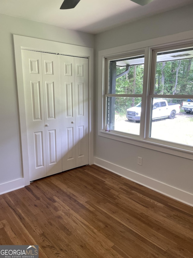 unfurnished bedroom with baseboards, dark wood-type flooring, and a closet