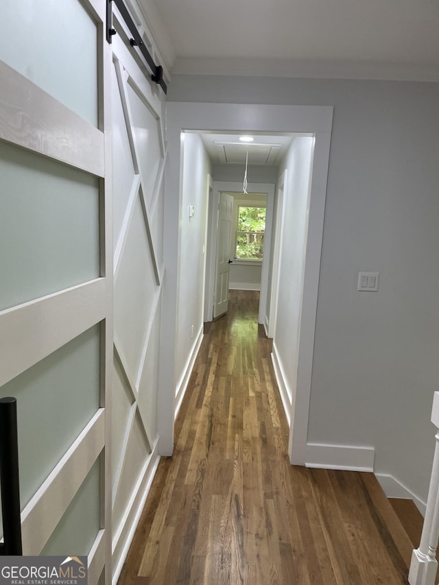 corridor featuring attic access, wood finished floors, and baseboards