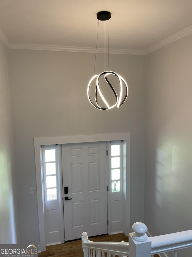 foyer with healthy amount of natural light, crown molding, and dark wood finished floors