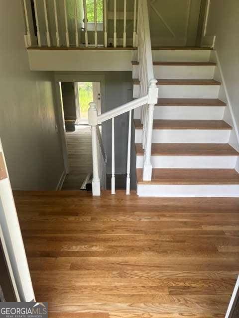 stairs with healthy amount of natural light and wood finished floors