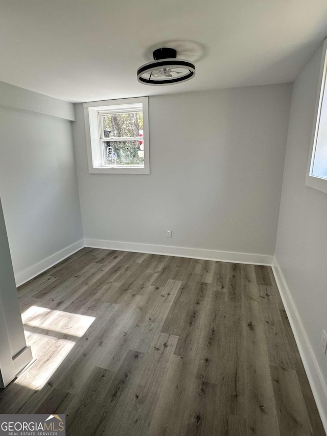 unfurnished room with wood finished floors, healthy amount of natural light, and baseboards