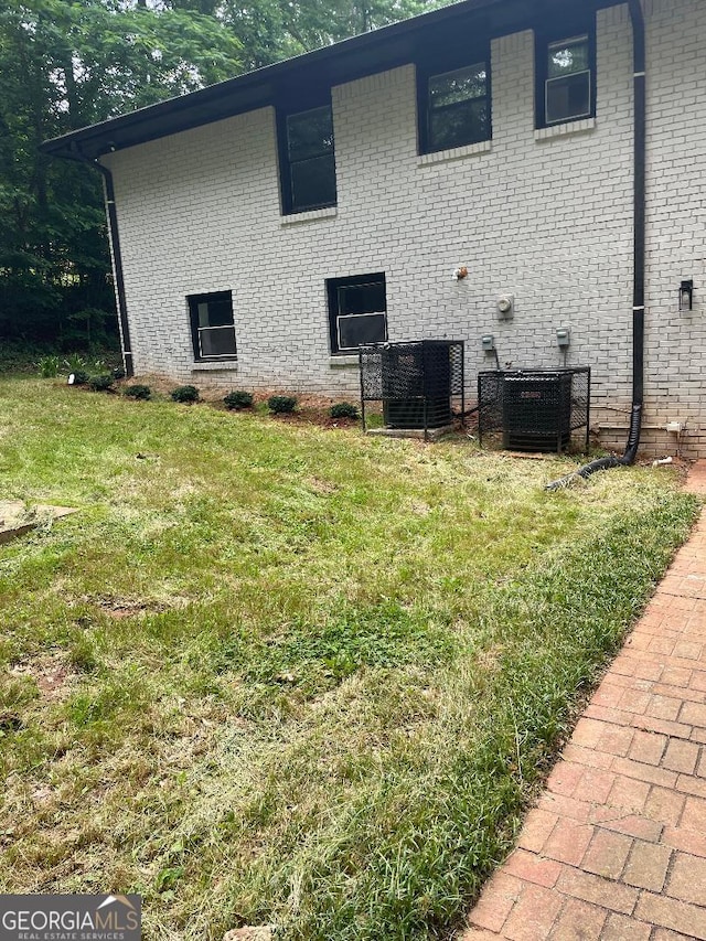 view of home's exterior featuring cooling unit, a yard, and brick siding
