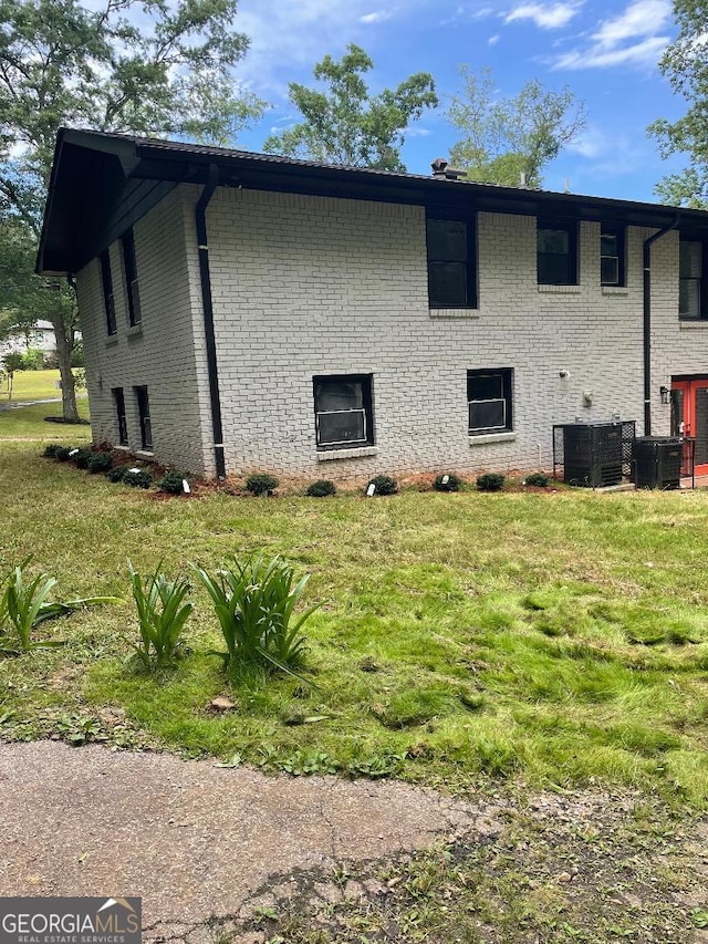 view of home's exterior with brick siding, central air condition unit, and a lawn