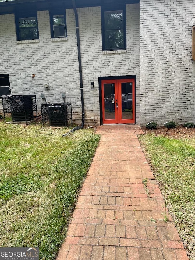 property entrance featuring french doors, cooling unit, and brick siding