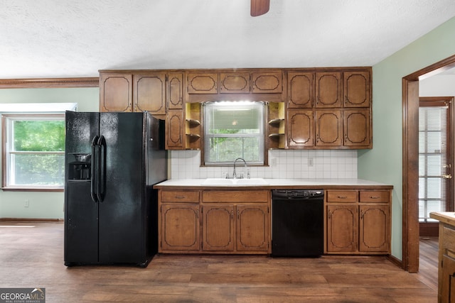 kitchen featuring black appliances, a sink, light countertops, backsplash, and a textured ceiling