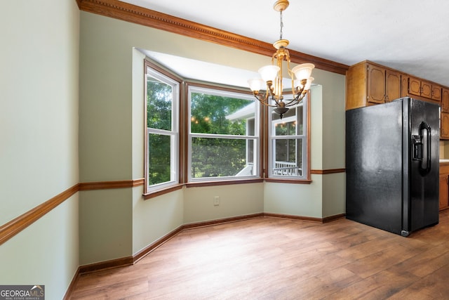 kitchen with black refrigerator with ice dispenser, a chandelier, light wood-style floors, and hanging light fixtures