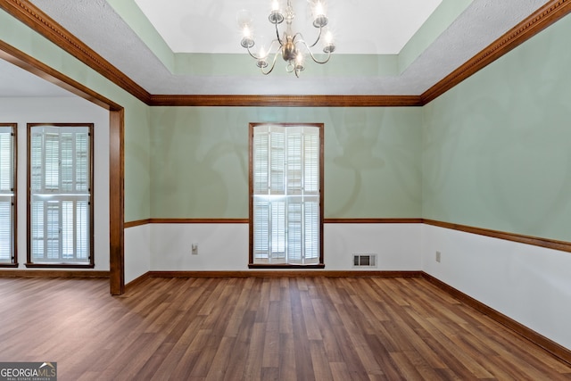 unfurnished room featuring wood finished floors, a chandelier, a tray ceiling, baseboards, and ornamental molding