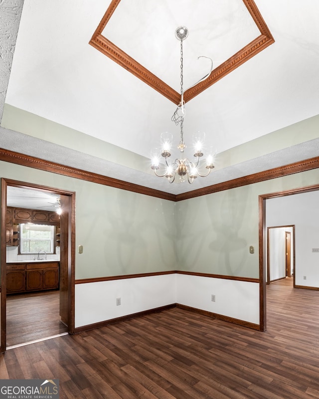 unfurnished room with a chandelier, dark wood-style flooring, baseboards, a sink, and ornamental molding