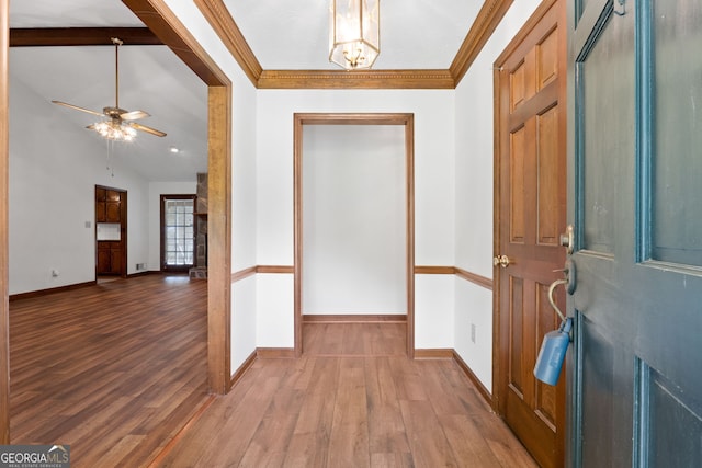 foyer featuring wood finished floors, baseboards, ceiling fan, crown molding, and a chandelier