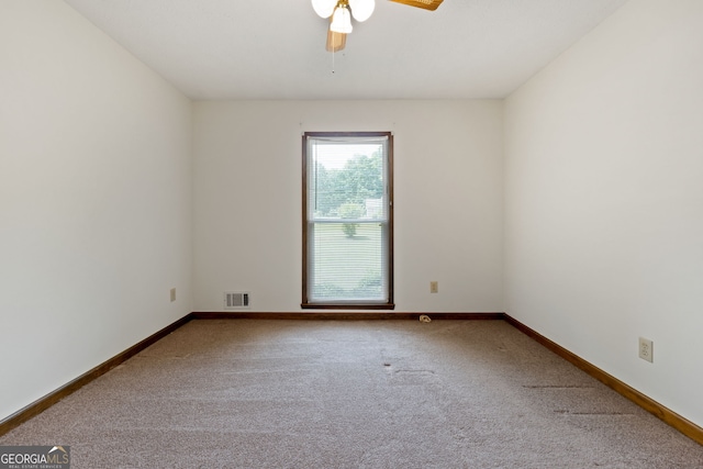 empty room with carpet floors, a ceiling fan, and baseboards