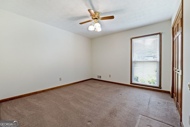 unfurnished room with carpet flooring, a ceiling fan, baseboards, and a textured ceiling