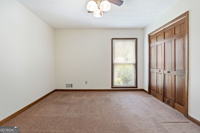 unfurnished bedroom featuring carpet, baseboards, a closet, ceiling fan, and a textured ceiling