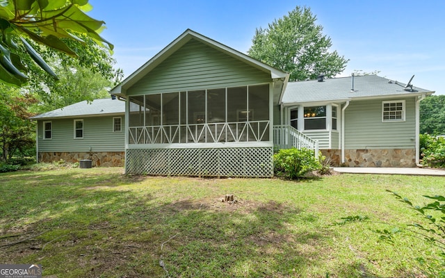 back of house featuring a sunroom, a lawn, and stone siding