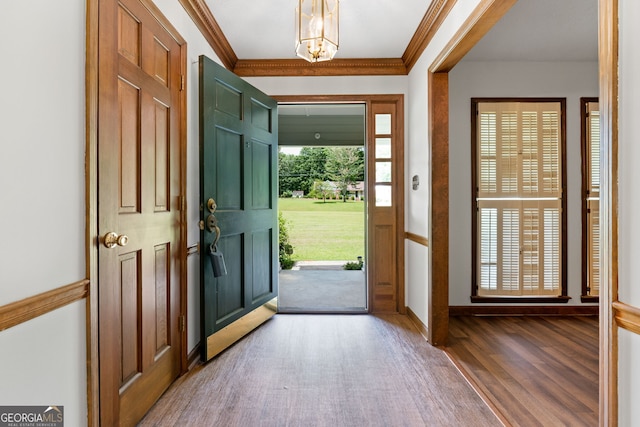 foyer entrance featuring wood finished floors, crown molding, and a chandelier