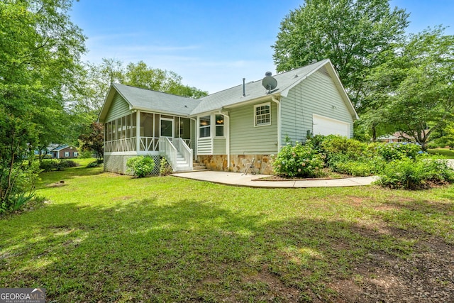 back of house with a sunroom, a lawn, and a garage