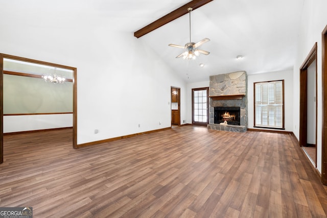 unfurnished living room with a stone fireplace, beamed ceiling, a chandelier, a ceiling fan, and wood finished floors