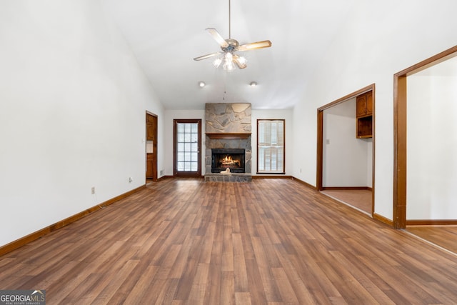 unfurnished living room featuring ceiling fan, baseboards, wood finished floors, a fireplace, and high vaulted ceiling