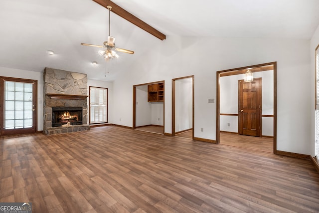 unfurnished living room featuring ceiling fan, wood finished floors, beamed ceiling, baseboards, and a stone fireplace